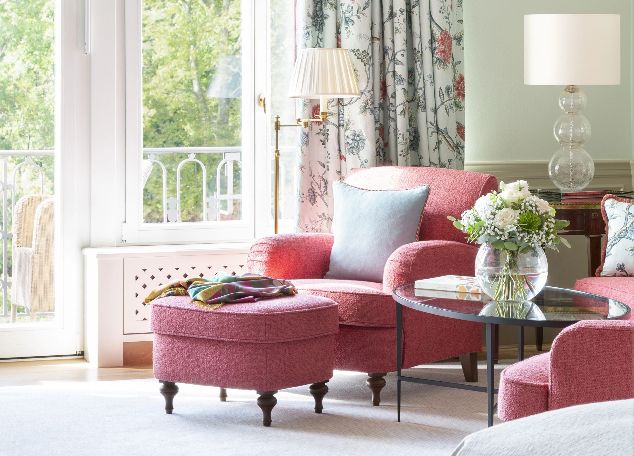 sala iluminada com poltronas vermelhas e vista para jardim