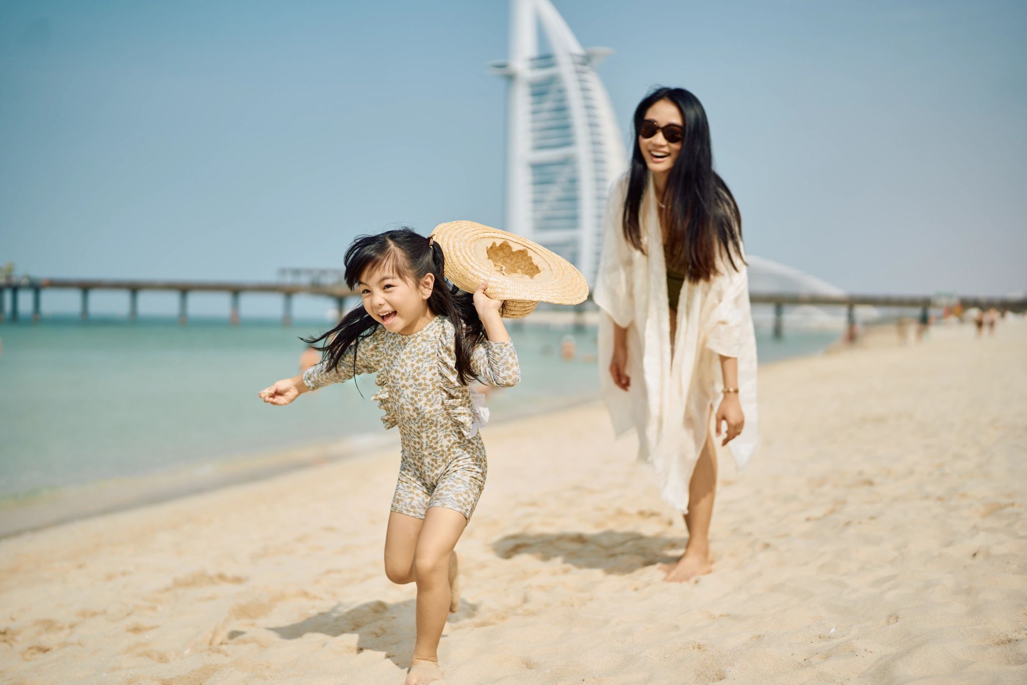 mulher e criança caminhando a beira-mar no resort em dubai