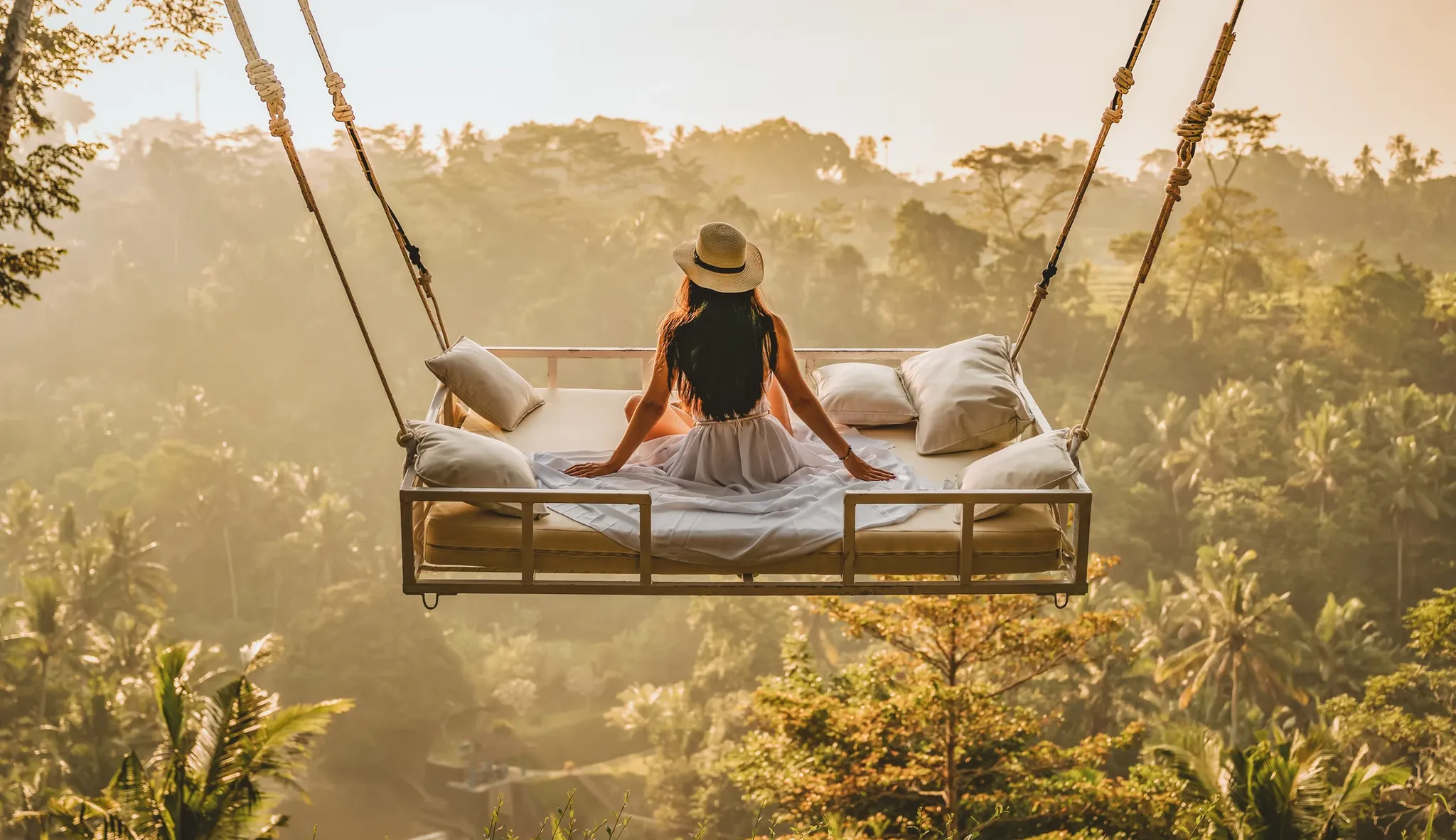 Mulher em um grande balanço sobre a copa de várias árvores