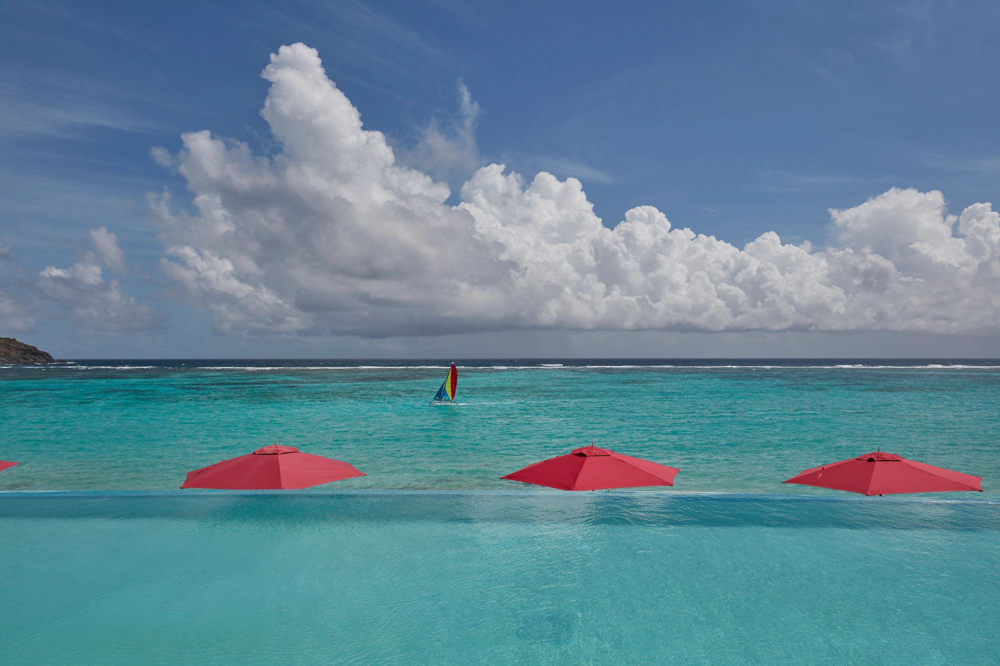 guarda sois vermelhos na areia - mar cristalino - piscina