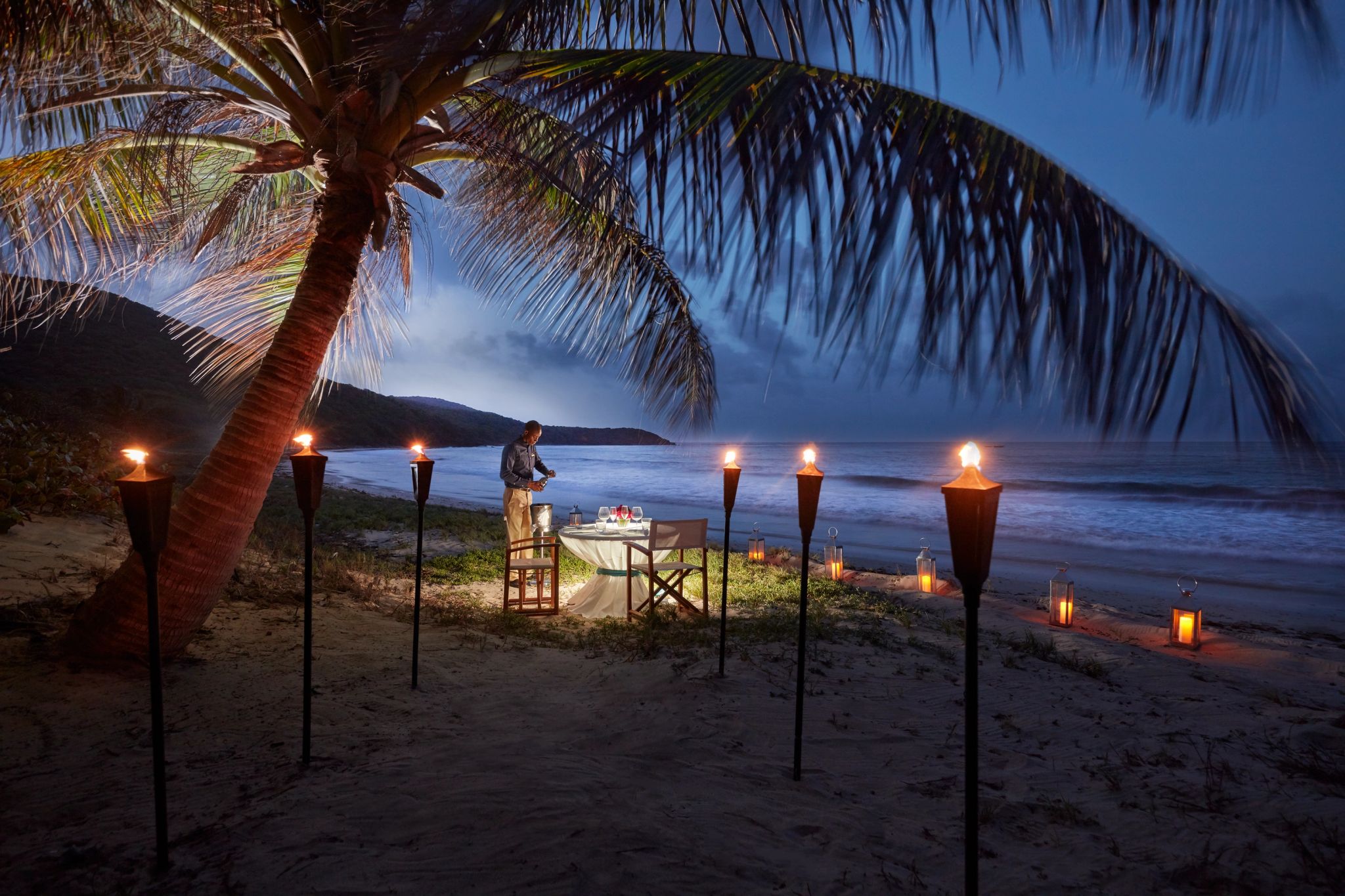 mesa montada na areia - luz de velas e tochas - por do sol