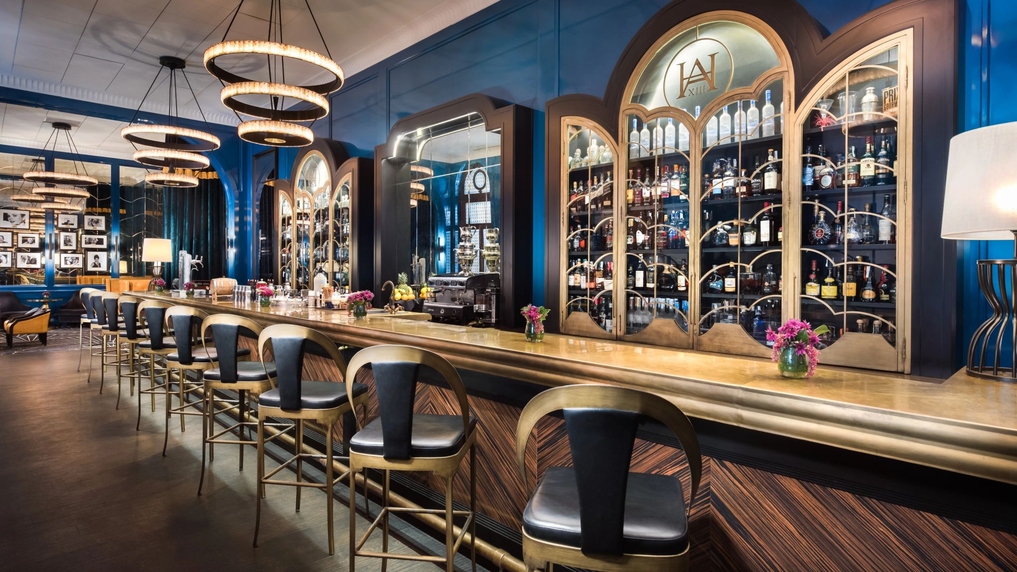 Bar Americano balcao de madeira escura com garrafas de bebidas e banquetas de couro - bar de luxo