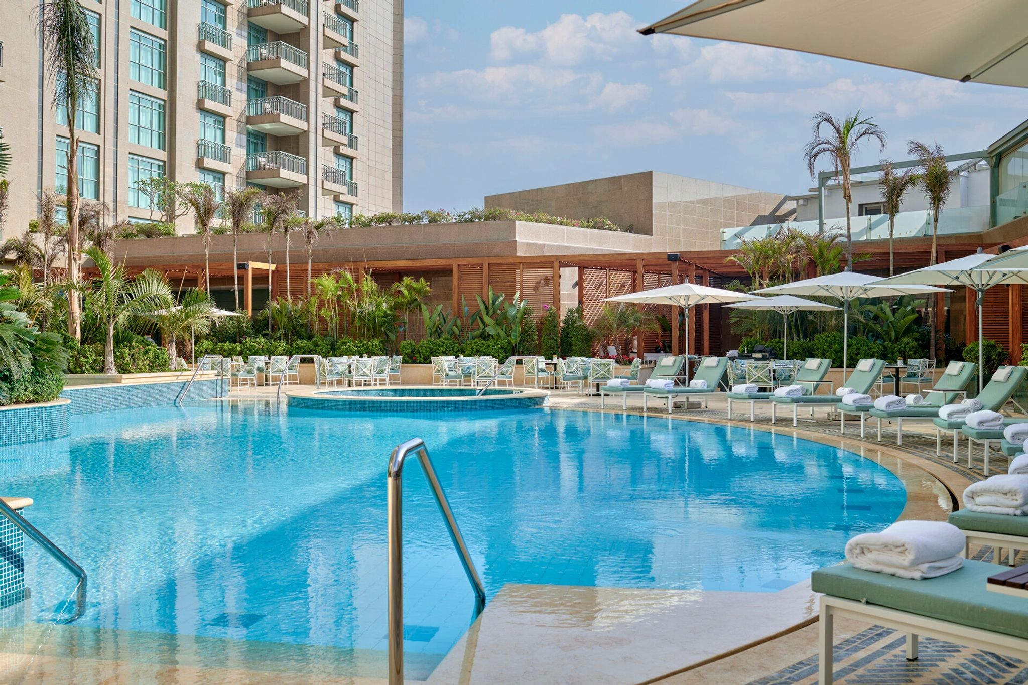 piscina externa cercada por espreguicadeiras em hotel de luxo